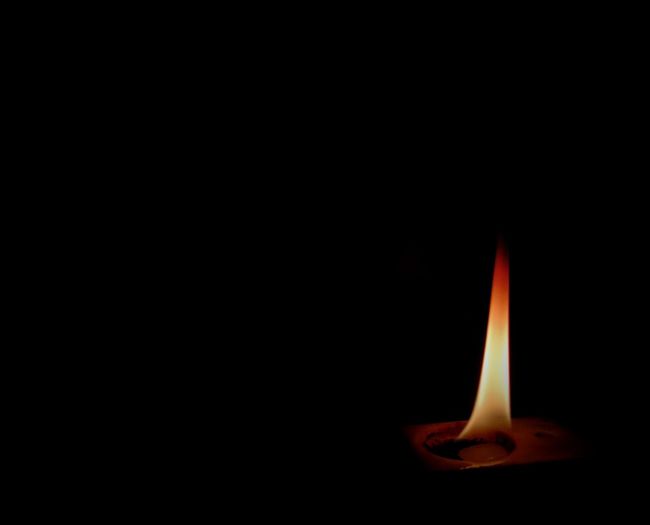 Close-up of lit candle in darkroom
