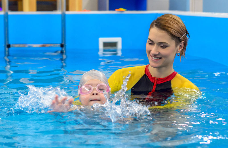 The coach teaches the child to swim in the pool