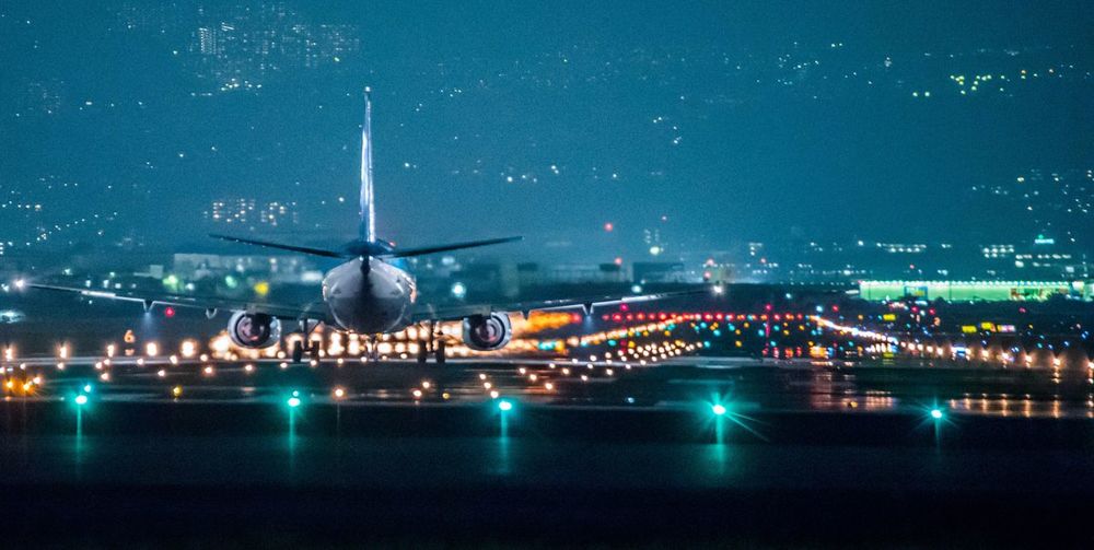 Airplane flying over illuminated city at night