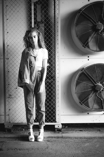 Portrait of teenage girl standing against exhaust fans