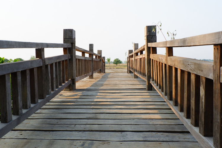Surface level of wooden footbridge against clear sky