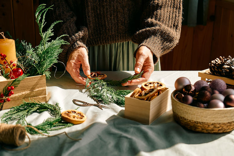 Woman making christmas arrangement with fir branches and dried oranges. winter holidays.