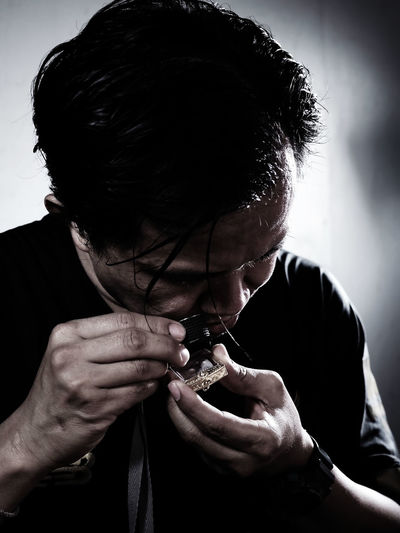 Close-up of man looking at amulet through loupe