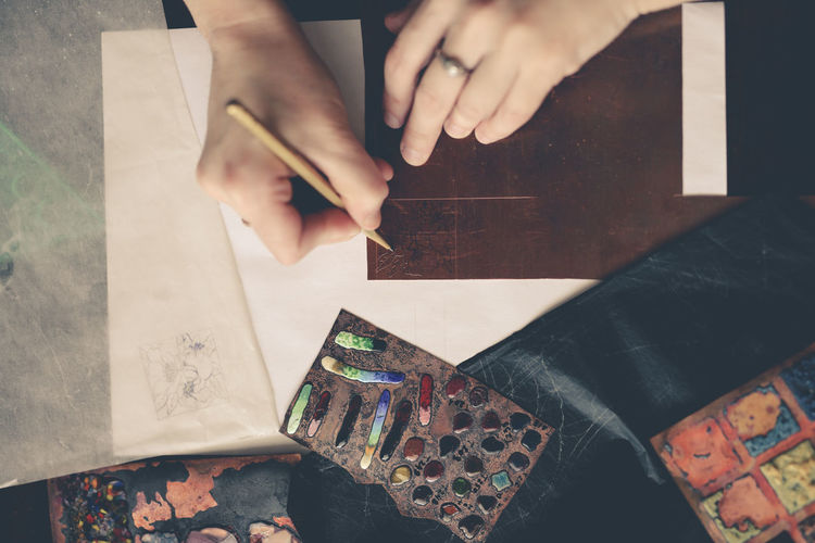 Drawing a sketch on a plate of copper with a metal pen, close-up, materials in a home creative