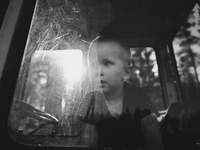 Close-up of boy looking through window in vehicle