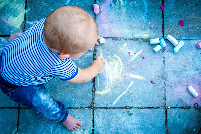 High angle view of boy playing with chalk 
