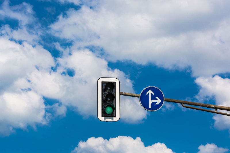Low angle view of road signal against cloudy blue sky