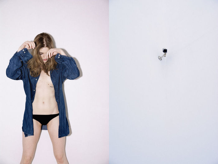Young woman wearing panties standing by wall