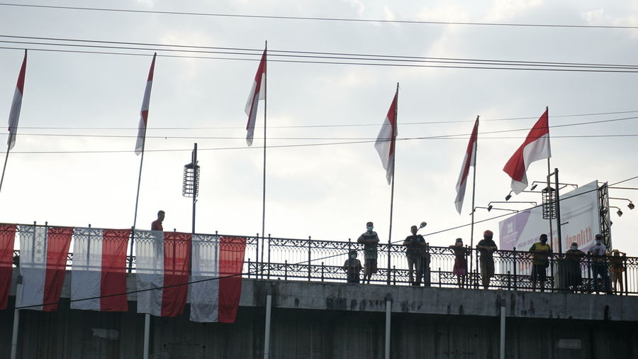 Low angle view of flags on bridge against sky