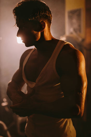 Muscular man standing amidst smoke in darkroom
