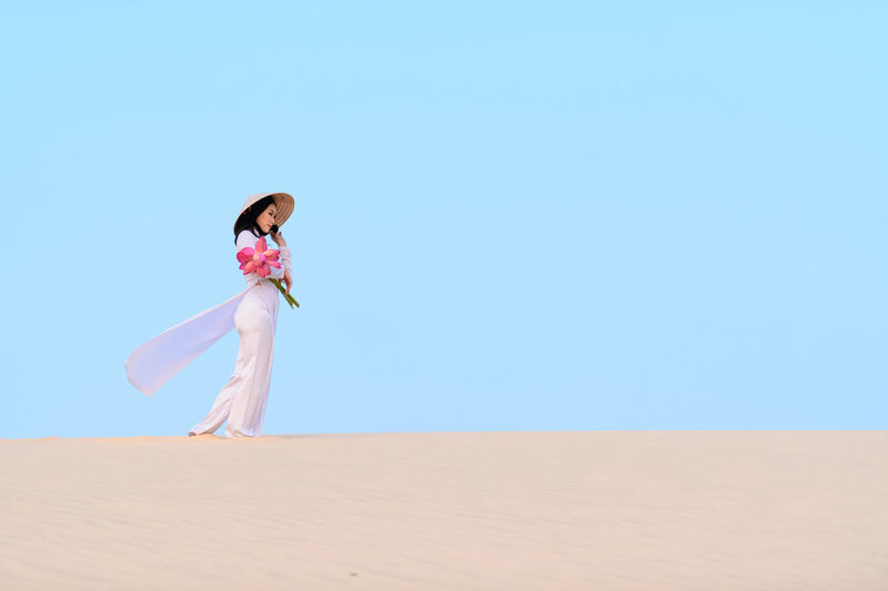 Woman on sand dune against clear sky