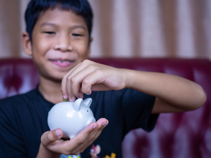Boy saving money in a white pig piggy bank.saving concept. saving for the future.