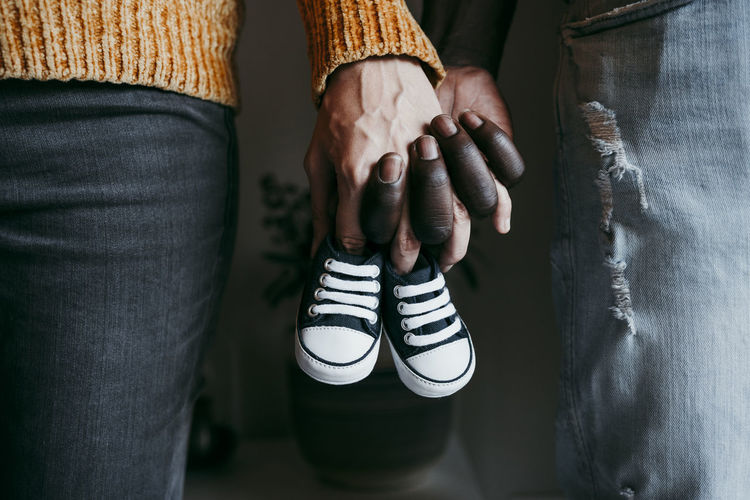Young man with pregnant woman holding baby booties at home