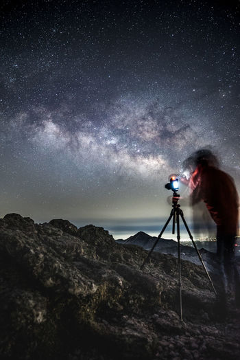 Double exposure of man photographing sky at night