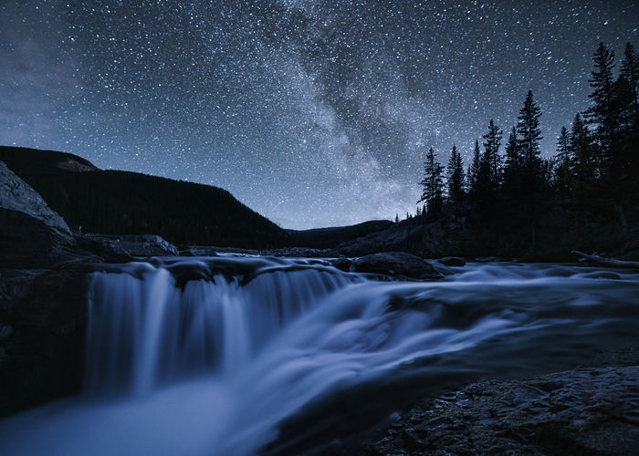 Scenic view of waterfall against sky at night