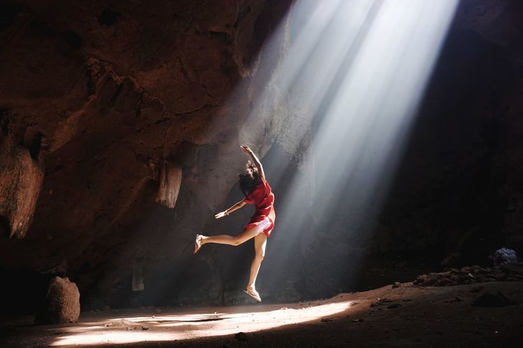 Carefree teenage girl dancing in cave