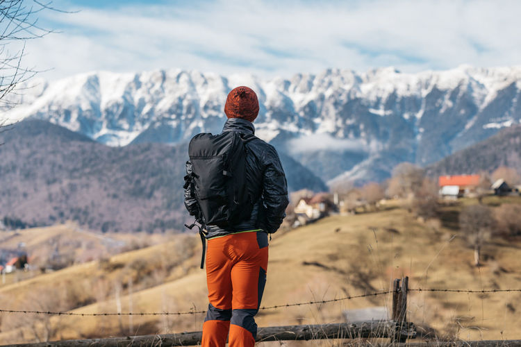 Man hiking in winter and admiring the amazing view towards the mountains.