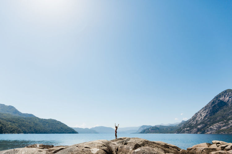Man standing on shore by sea against clear sky