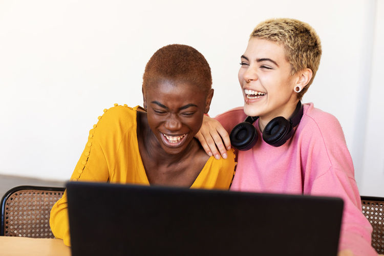 Cheerful lesbian couple looking at laptop