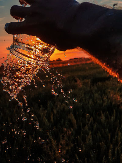 Close-up of hand holding glass during sunset