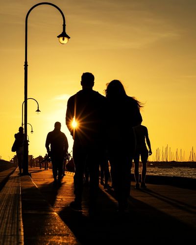 Silhouette people on pier over sea against sky during sunset