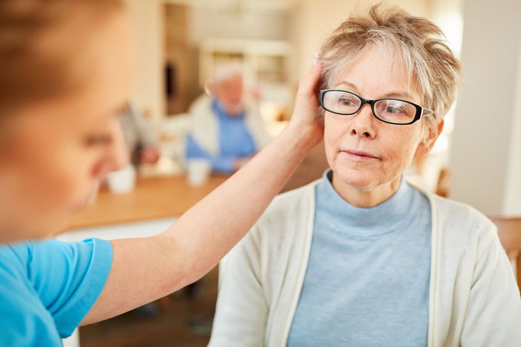 Close-up of female nurse consoling senior woman in nursing home