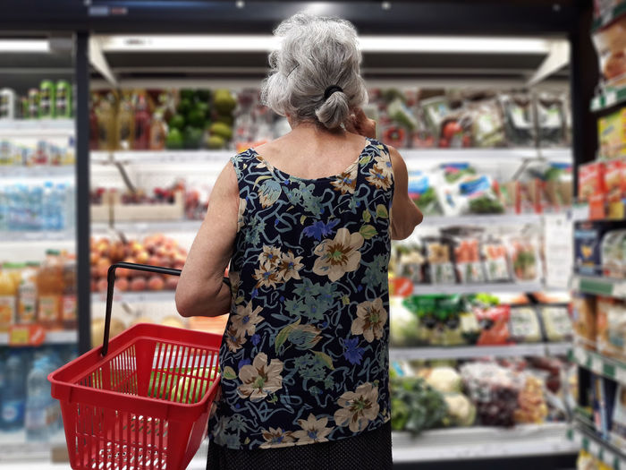Rear view of senior woman shopping in supermarket