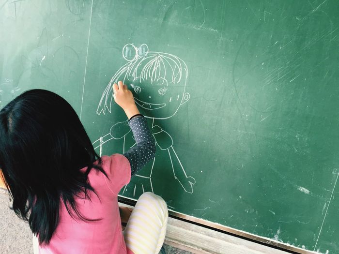 Girl drawing on blackboard in classroom