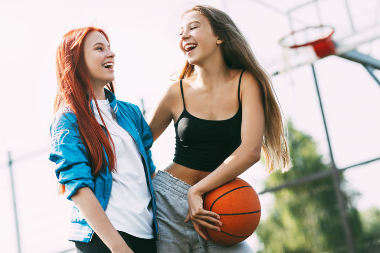 Two funny girls with a basketball hug each other after a game or workout. the concept of sports 