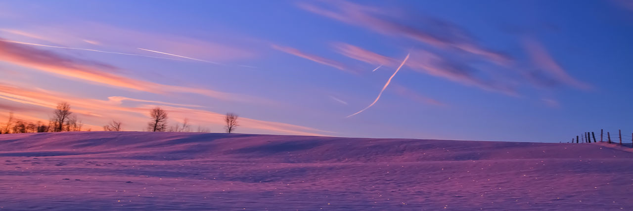 Scenic view of snowcapped landscape against sky at sunset