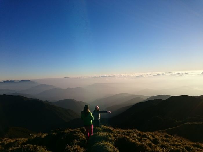 Mother and daughter standing on mountain top