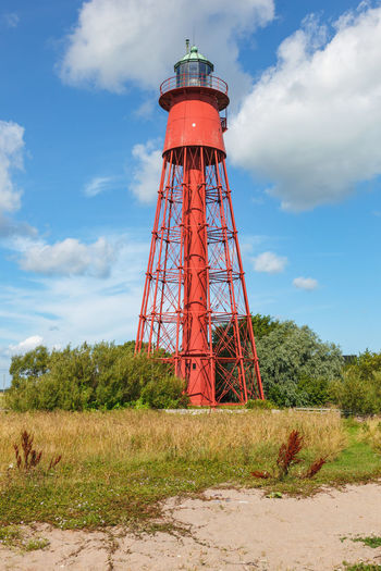 Red steel lighthouse on the sandy beach