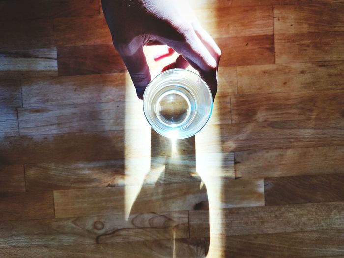 High angle view of hand holding glass of wooden table