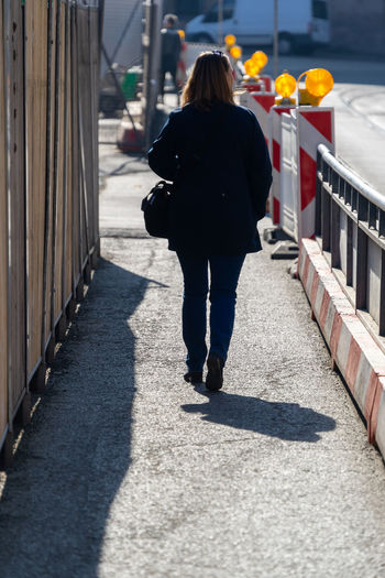 Rear view of woman walking on footpath