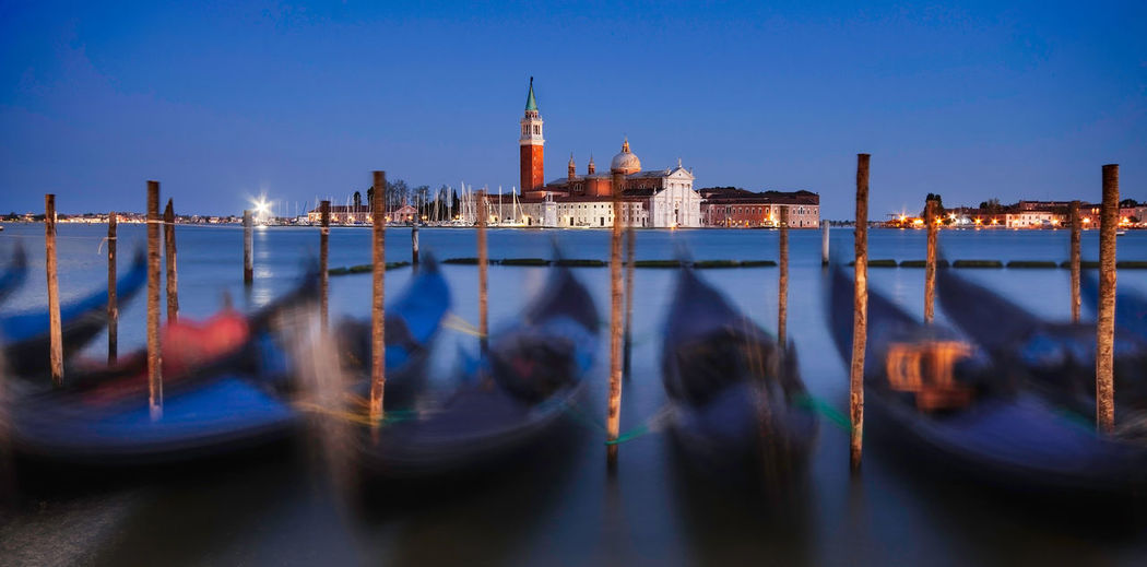 Long exposure of gondolas moored on canal against sky