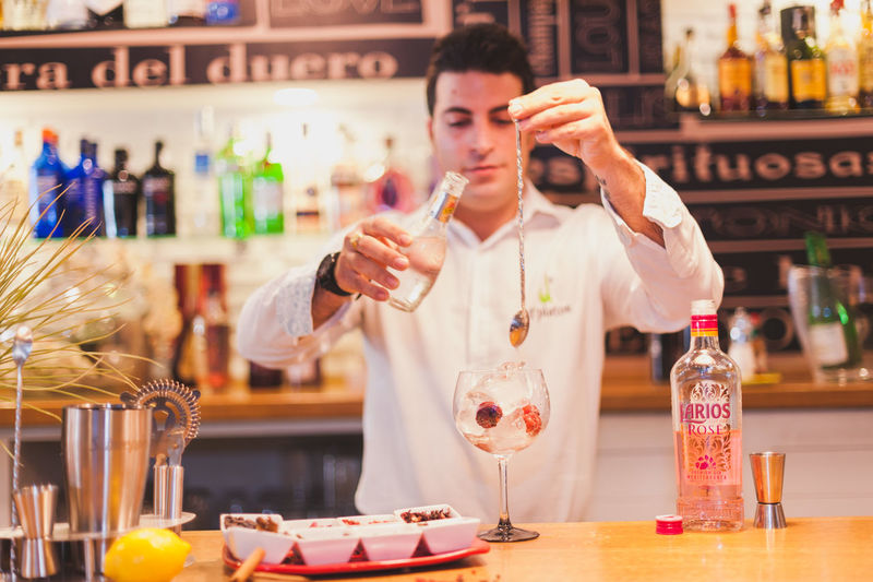 Young bartender preparing drink at counter