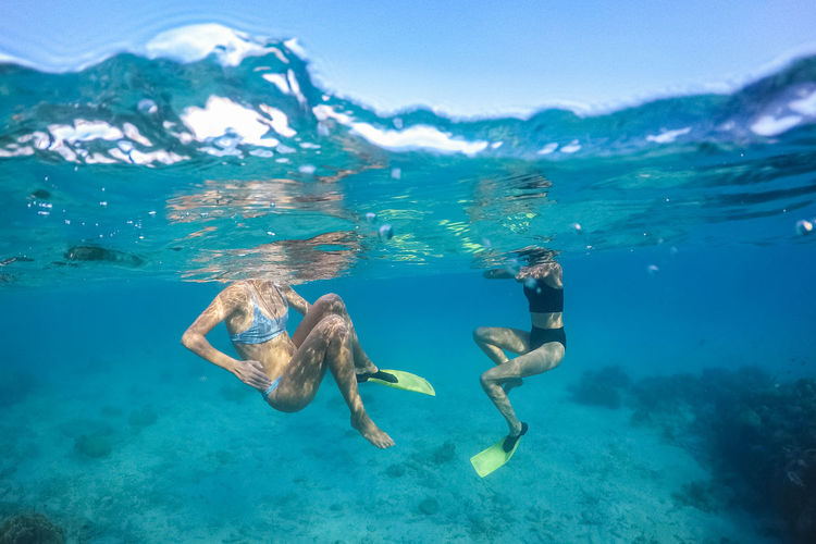 Females in swimsuit swimming under sea