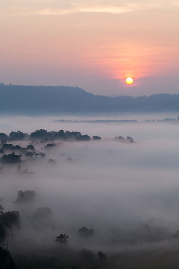 Scenic view of fog against sky during sunset
