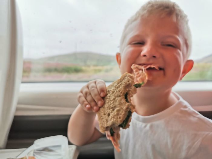 Boy holding sandwich against train window