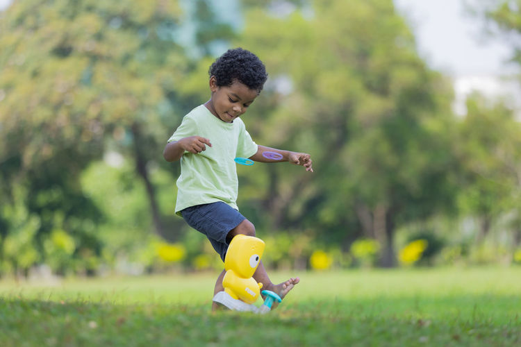 Side view of boy playing with toy on field