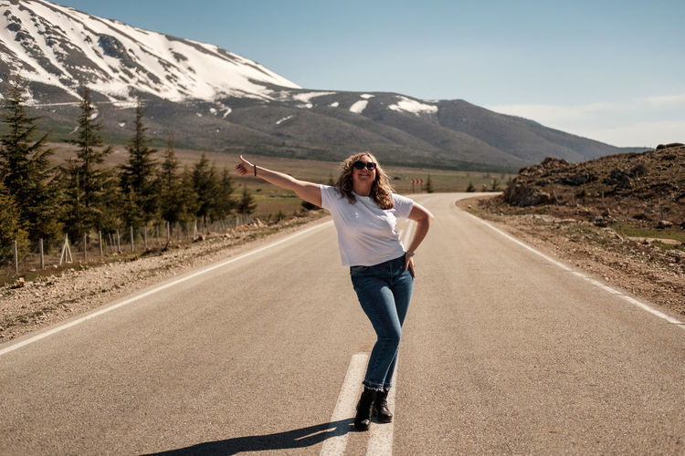 Girl hitchhiking on a mountain road