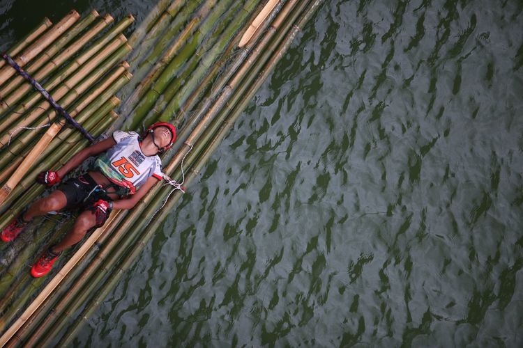 High angle view of man lying on wooden raft over river