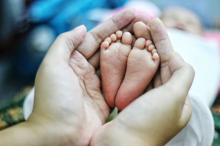 Cropped image of mother holding the legs of baby