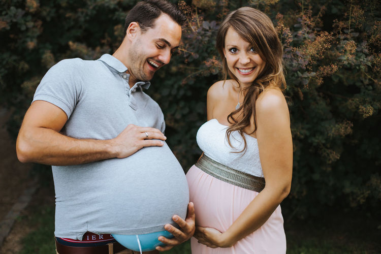Pregnant woman making face while holding husband stomach