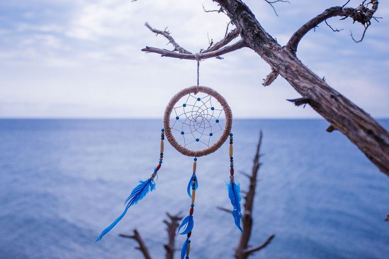 Close-up of dreamcatcher hanging over sea against sky