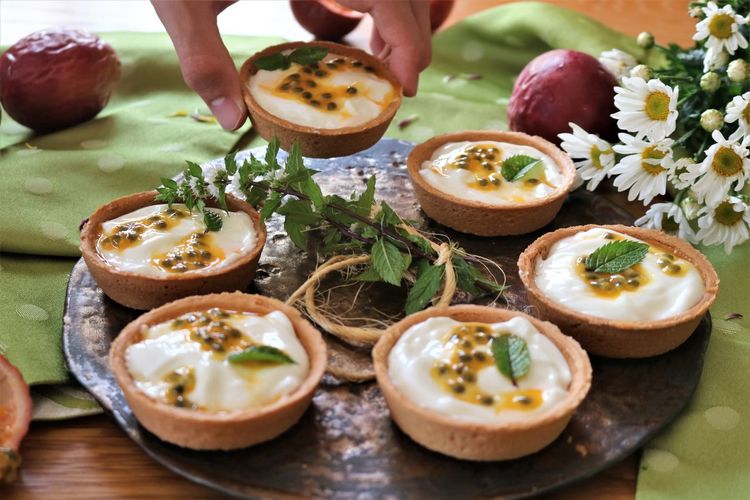 Close-up of person taking fruit pastries on table