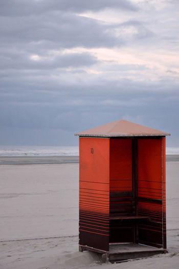 Beach hut against cloudy sky