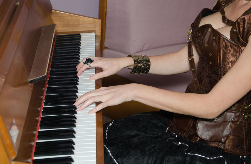 Midsection of woman playing piano at home
