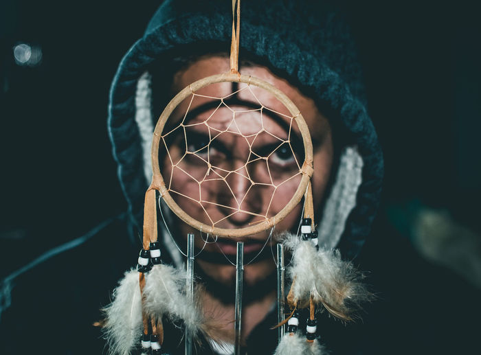 Close-up portrait of young man looking through dreamcatcher