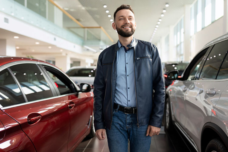 Portrait of young man standing in car show room